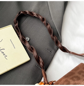 Close-up of a dark brown woven leather strap with retro wooden beads on a stylish handbag