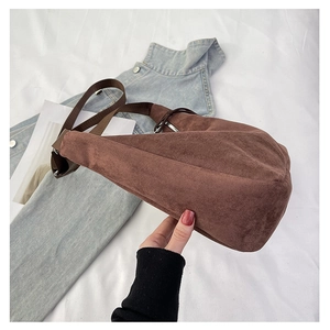 Detail of a brown suede half-moon bag featuring a durable canvas strap and silver zipper