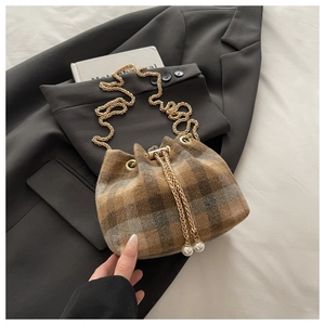 Detail view of retro plaid bucket bag with gold chain and pearl drawstring charms