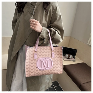 Detail of pink monogram tote bag with embossed M logo in a professional office setting