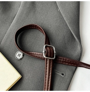 Close-up of dark brown leather strap featuring a silver square buckle and stitching