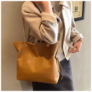 Chic caramel leather bucket bag with gold chain strap and elegant tassel detail