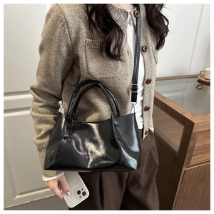 Détail d'un sac cabas en cuir verni noir brillant avec doubles poignées et bandoulière