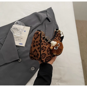 Detailed macro view of leopard print plush bag with gold chain and bear charm detail