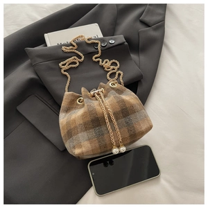 Detail of brown plaid bucket bag with gold chain strap and pearl drawstring charm