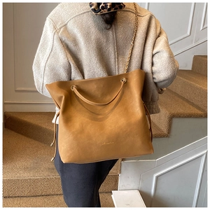 Detail view of khaki bucket bag showing metal chain strap and side drawstring texture