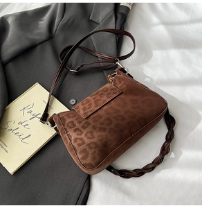 Detail of leopard print suede shoulder bag with brown woven handle on a suit