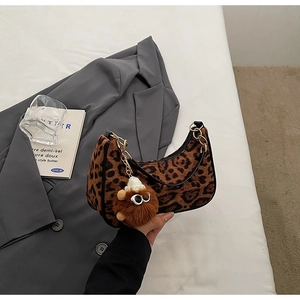 Close-up of leopard print hobo bag with gold chain and plush toy charm detail