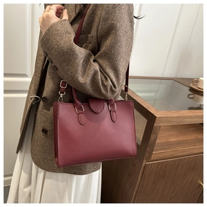 Detail of wine red pebble leather tote bag with gold hardware and removable shoulder strap