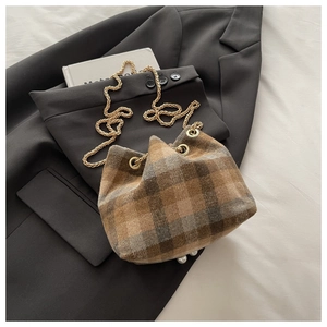 Close-up of brown plaid wool bucket bag with pearl details and golden chain strap