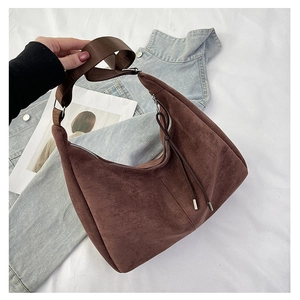 Close-up of deep brown suede tote with wide woven strap and fringe zipper detail