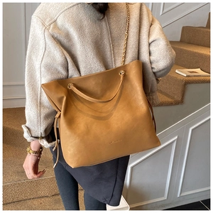 Detail of camel leather bucket bag with metallic chain strap and drawstring accents