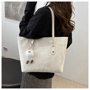Close-up of white tote bag with cloud texture, plush charm, and reinforced gold rivets