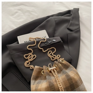 Detail of vintage plaid bucket bag with gold chain strap on a grey blazer