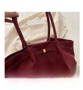 Vue détaillée du cuir grainé bordeaux et de la boucle dorée sur le sac fourre-tout