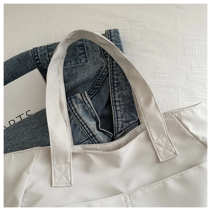 Close-up of white nylon tote bag showing reinforced cross-stitching and high-quality texture