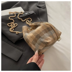 Close-up of brown plaid wool bucket bag with gold chain drawstring and pearl charms
