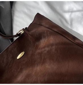 Close-up of deep brown leather tote bag with elegant gold metal buckles and hardware
