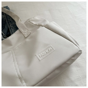 Detailed close-up of nylon fabric texture and Fashion patch on a minimalist tote bag
