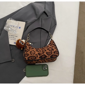 Détail d'un sac à bandoulière léopard avec breloque en peluche et chaîne dorée