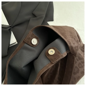 Detailed macro view of magnetic clasps and leopard print suede fabric texture on tote bag