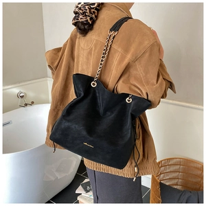 Detail of black bucket bag with golden chain strap and logo on high-quality matte leather
