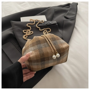 Detailed shot of plaid pattern fabric with gold chain strap and pearl decor on handbag