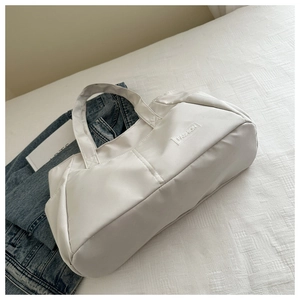 Detail of white nylon tote bag with Fashion label and water-resistant smooth texture