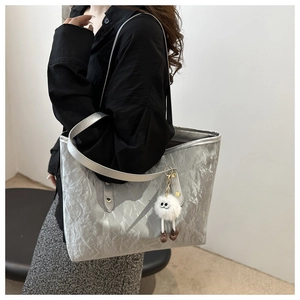 Silver metallic tote bag detail with textured crinkle finish and plush charm accessory