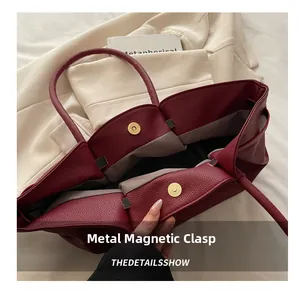 Vue détaillée du fermoir magnétique doré d'un sac cabas bordeaux avec doublure grise