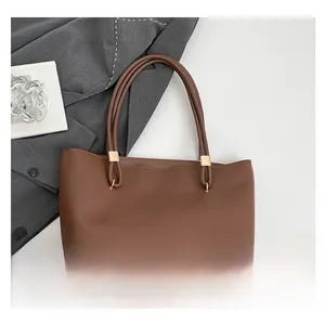 Close-up of brown matte leather tote bag featuring unique wave-cut edge and gold buckles
