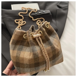 Detail of plaid wool bucket bag with gold chain strap and pearl drawstring accents