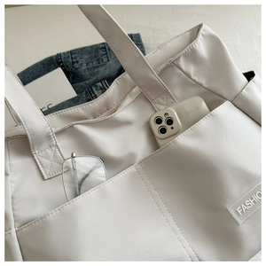 Close-up of white multi-pocket nylon tote bag with Fashion label for daily commuting