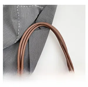 Detail of coffee brown leather tote handle with polished gold metal buckles and stitching