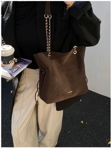 Detail of coffee brown suede tote bag with golden chain strap and side drawstring