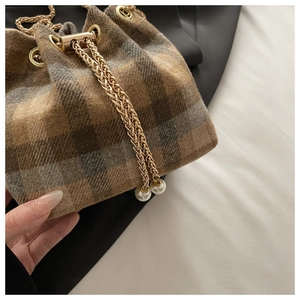 Close-up of checkered wool bucket bag with gold chain drawstring and pearl details