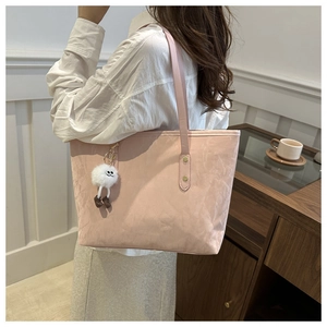 Detailed view of a soft pink tote bag featuring a cute white plush monster pendant detail