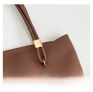 Detail of premium brown leather tote bag with gold metal buckle and neat stitching