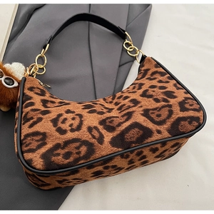 Close-up of leopard print crescent bag with black leather trim and plush animal charm