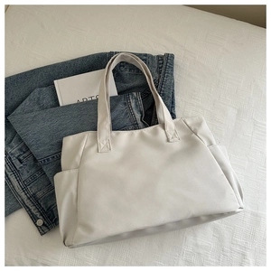 Detailed top view of a large cream tote bag with side pockets and sturdy woven handles