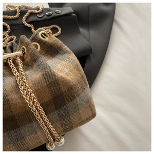 Close-up of winter plaid bucket bag featuring tweed texture and pearl chain drawstring