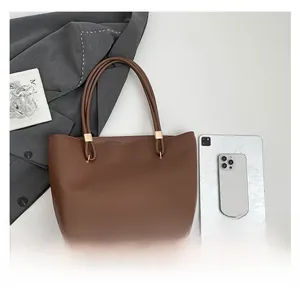 Detail of spacious dark brown tote bag showing golden hardware and interior capacity