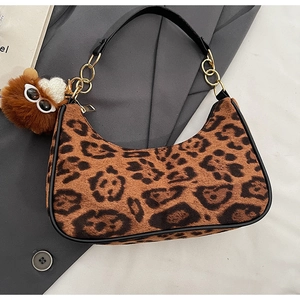 Detail of faux fur leopard print hobo bag with gold chain strap and plush monster charm