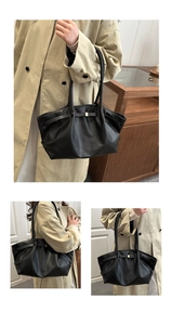 Close-up of black pebbled leather tote bag with gold buckle on beige trench coat