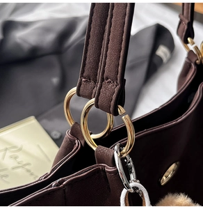 Detailed close-up of the golden metal buckle and stitching on the brown leather tote bag