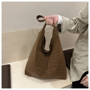 Detail of leopard print tote bag with matte texture and wide shoulder handle on model