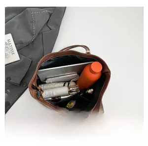 Top view of spacious interior in brown leather tote bag with tech and daily essentials
