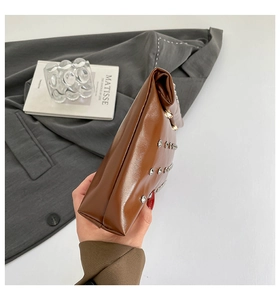 Gros plan sur un sac en cuir marron brillant orné de rangées de clous métalliques