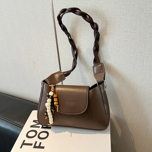Retro brown leather underarm bag with braided strap and decorative beads on white stand