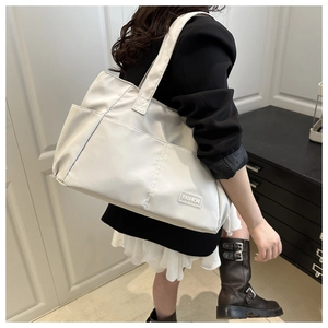 Detail view of lightweight off-white tote bag featuring a side pocket and fashion patch